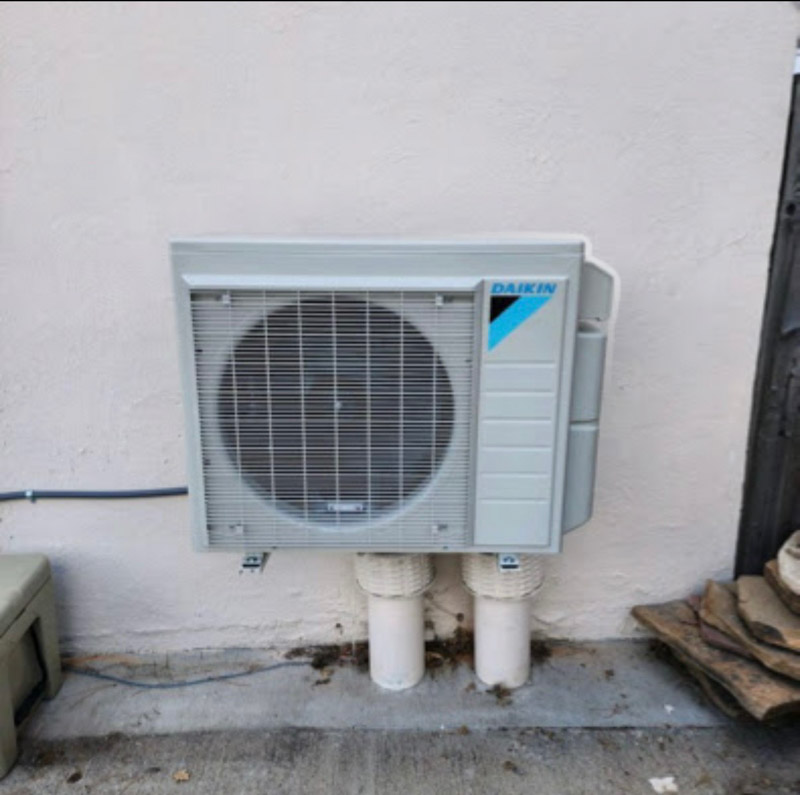 Wall-mounted Daikin mini-split outdoor unit with protected line connections