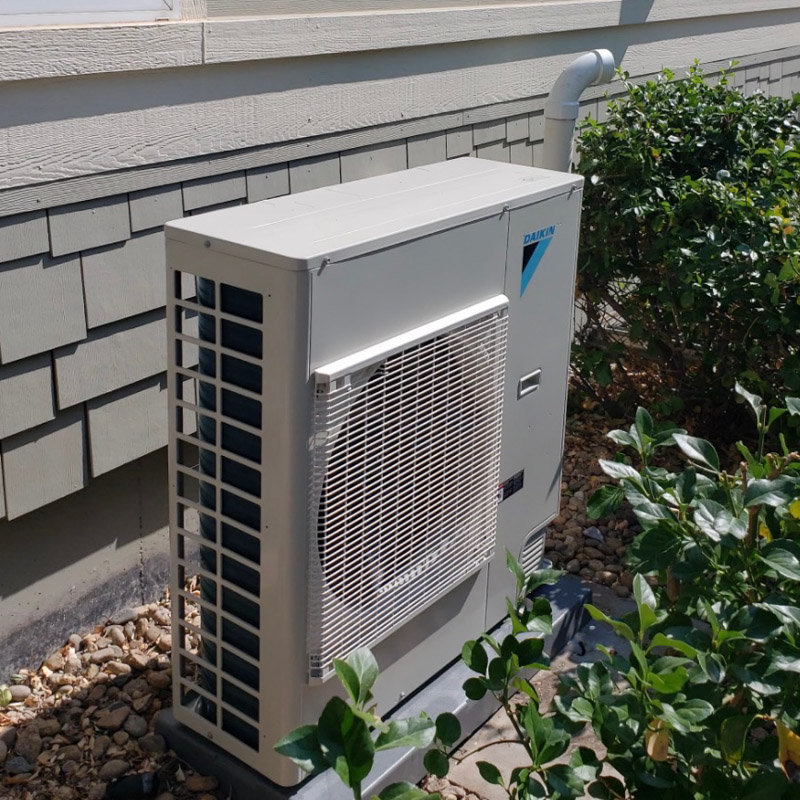 Daikin heat pump installed beside a home and landscaping