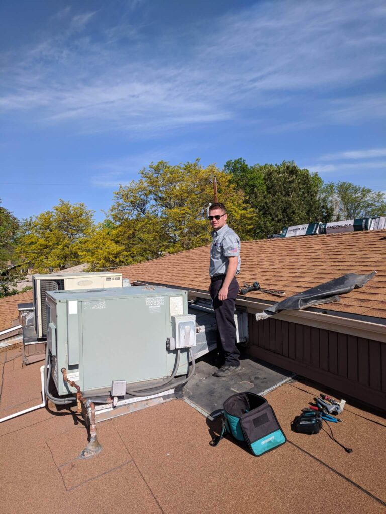 Apple Aire employee standing with a rooftop HVAC unit