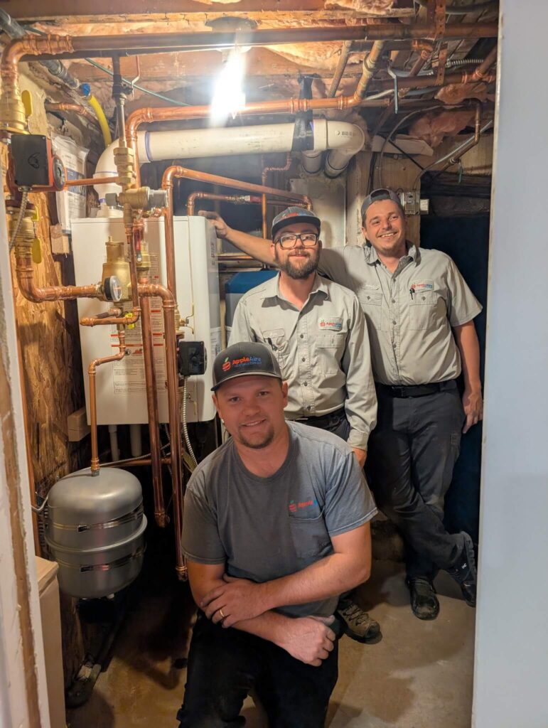 Apple Aire Employees standing next to a basement heating repair job
