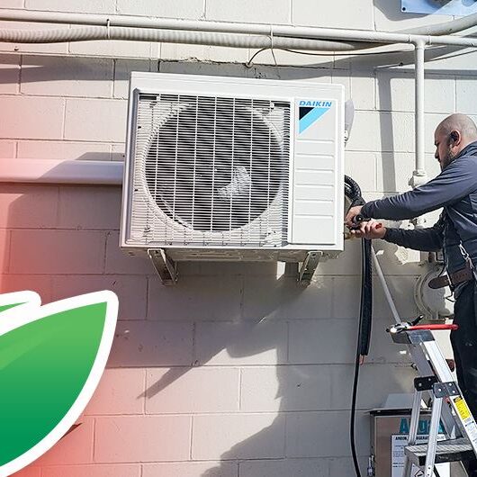 Daikin Equipment installation by tech standing on a ladder with a low profile heating and cooling unit on the side of a brick building