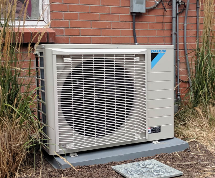 Energy Efficient Daikin heating and cooling unit on the side of a brick home.
